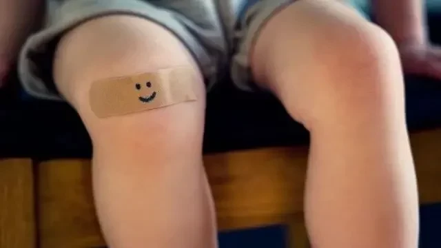Criança com curativo no joelho