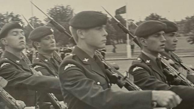 Imagem em preto e branco mostra jovens integrantes do Regimento de Paraquedistas marchando em um pátio de formatura. Os soldados carregam fuzis SA80 com baionetas fixadas