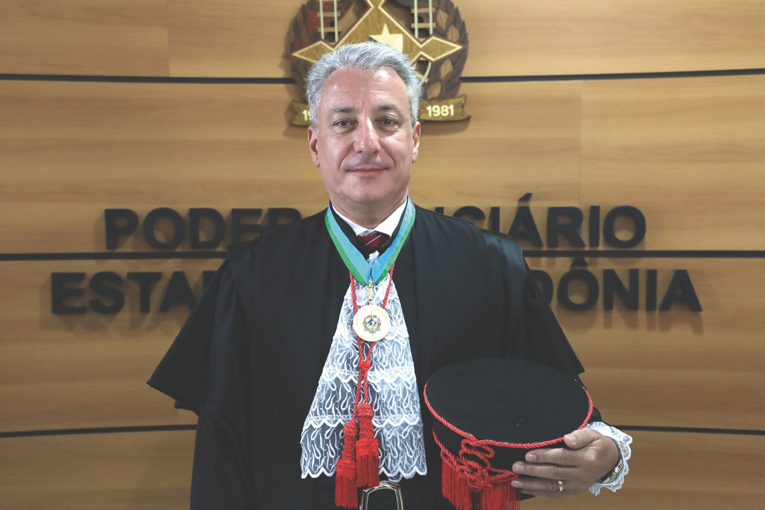 Homem branco trajado com roupaz de juiz posado para foto 