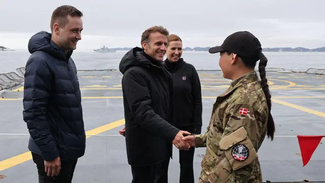 O presidente da França, Emmanuel Macron, cumprimenta uma oficial militar, ao lado do primeiro-ministro da Groenlândia, Jens-Frederik Nielsen, e da primeira-ministra da Dinamarca, Mette Frederiksen
