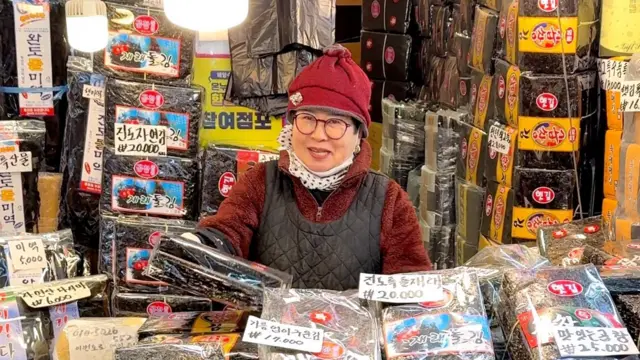 A woman standing in front of a seaweed shop 