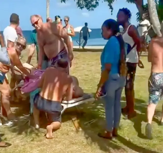 Peter Smith deitado na praia após o ataque, cercado por pessoas